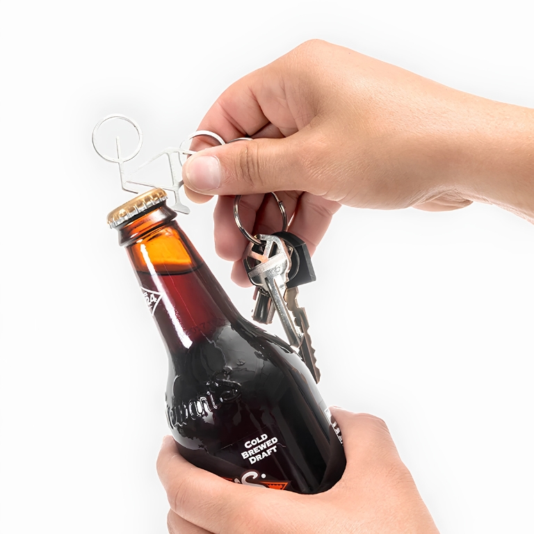 Hand gebruikt de Kikkerland fiets sleutelhanger als flesopener om een kroonkurk van een glazen fles te verwijderen