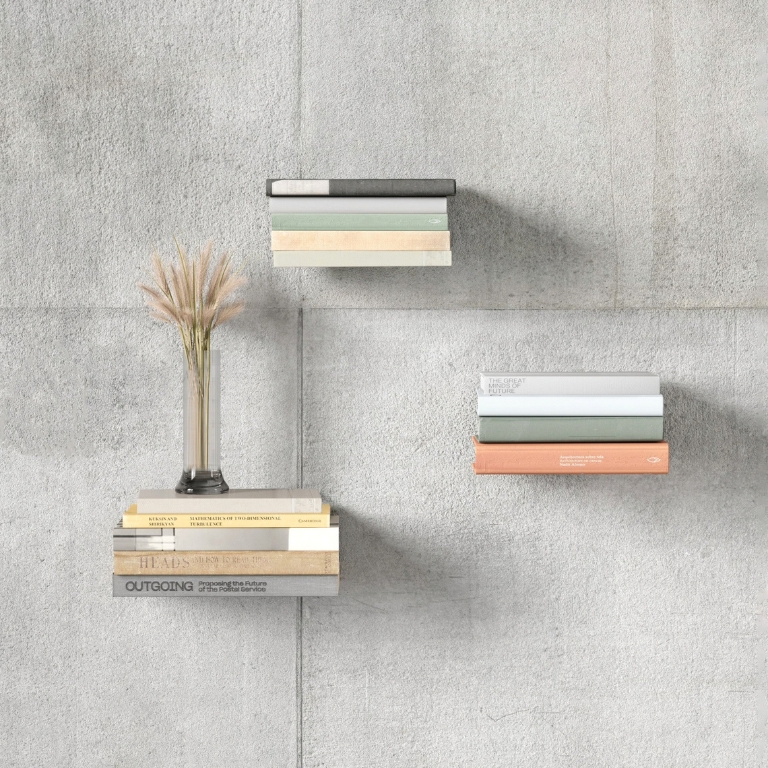 Drie stapels boeken op onzichtbare boekenplanken tegen een grijze betonmuur, met een vaas op de onderste stapel