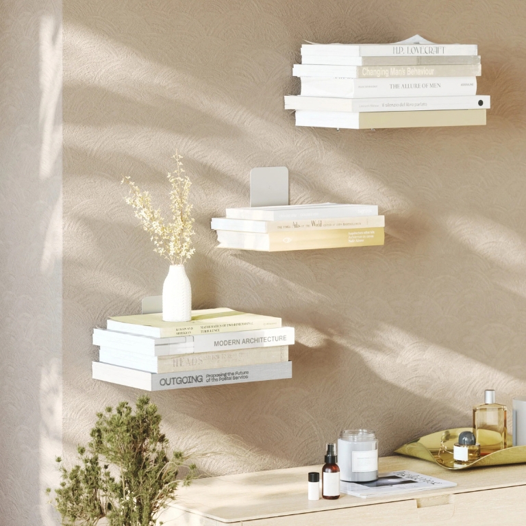 Zwevende boekenplanken met boeken en een kleine witte vaas aan een beige muur boven een houten kast