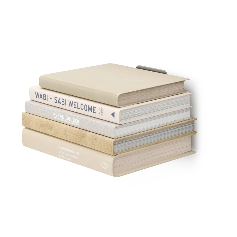 Stapel boeken op een Umbra Conceal zwevende boekenplank tegen een witte achtergrond, met de steun vrijwel onzichtbaar